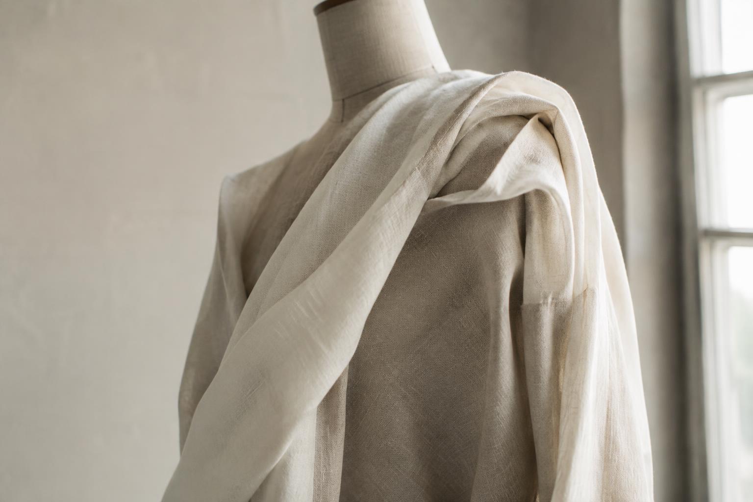Natural ivory linen fabric draped on a dress form in an atelier